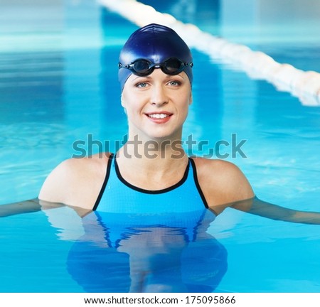 Young woman wearing blue swimming suit and cap in swimming pool