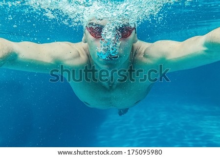 Man in swim cap and googles under water in swimming pool