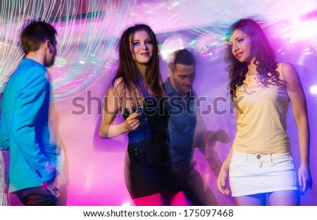 Group of happy young people dancing at night club
