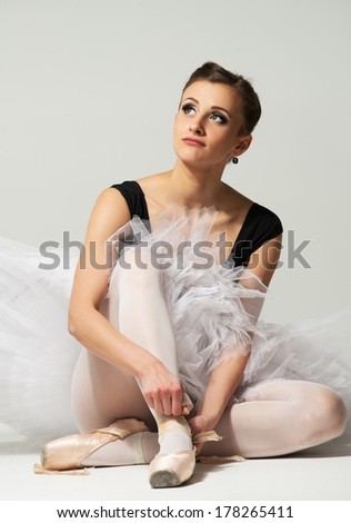 Beautiful young ballerina dancer sitting on a floor