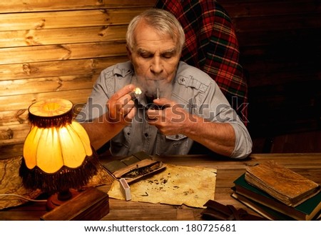 Senior man with smoking pipe in homely wooden interior