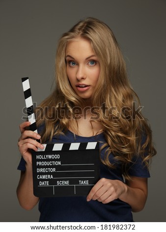 Young woman with long hair and blue eyes holding cinema clapper board