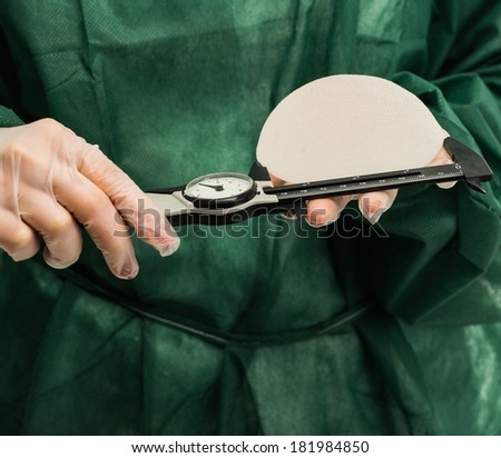 Plastic surgeon hands measuring silicon breast implants with calliper