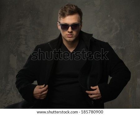 Stylish young man in black coat and sunglasses