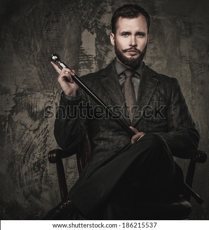 Handsome well-dressed with stick sitting in leather chair