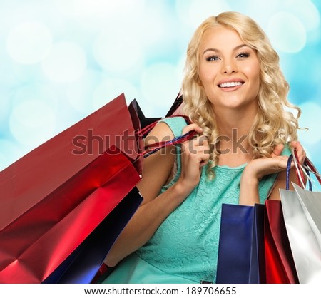 Smiling young blond woman with shopping bags over blurred background