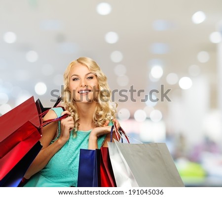Smiling young blond woman with shopping bags in clothing store
