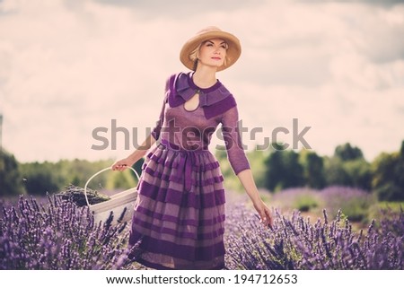 Woman in purple dress and hat with basket in lavender field