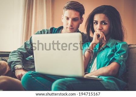 Young multi ethnic students couple preparing for exams in home interior
