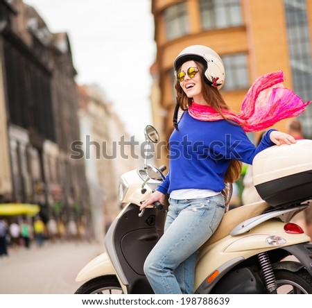 Young cheerful girl driving scooter in in european city