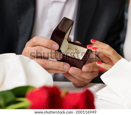 Man holding box with ring making propose to his girlfriend