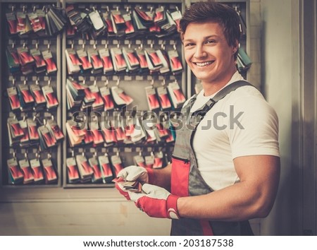 Cheerful serviceman near stand with colour samples in car body workshop