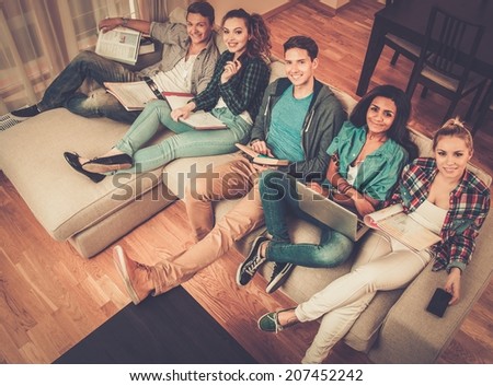 Group of multi ethnic young students preparing for exams in home interior