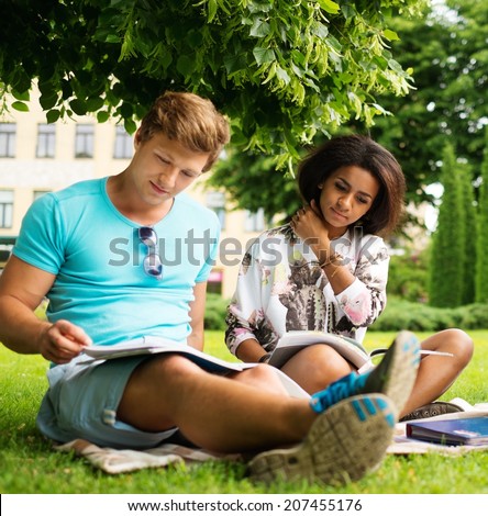 Multi ethnic students couple preparing for final exams in a city park