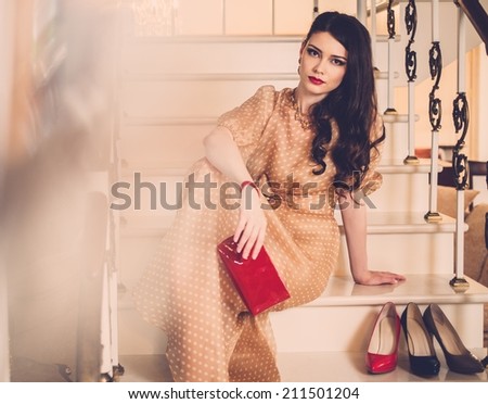 Beautiful young lady sitting on a steps in luxury house interior