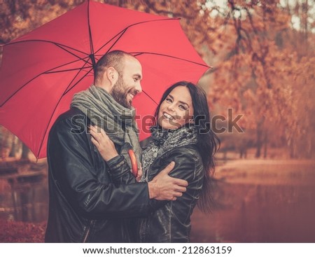 Happy middle-aged couple with umbrella outdoors on beautiful rainy autumn day