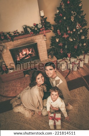 Family near fireplace in Christmas decorated house interior with gift box