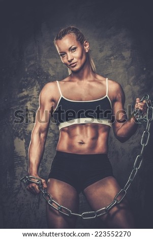Beautiful muscular bodybuilder woman holding chains