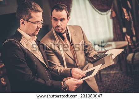Tailor and client choosing cloth and buttons for custom made suit