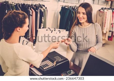 Happy woman customer paying with credit card in fashion showroom