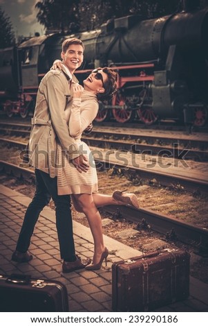 Vintage style couple with suitcases on train station platform