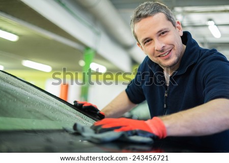 Cheerful worker wiping car on a car wash