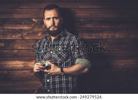 Man with beard in checkered shirt holding camera