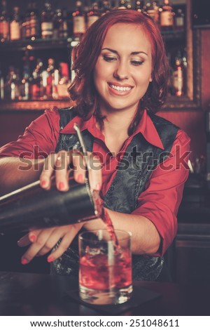 Beautiful redhead barmaid making cocktail