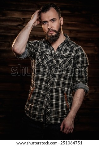 Handsome man wearing checkered  shirt in wooden rural house interior
