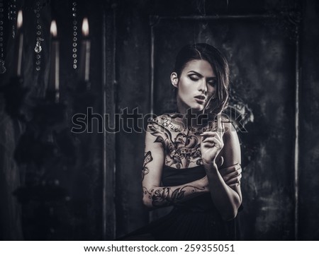 Smoking tattooed beautiful woman  in old spooky interior