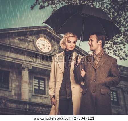 Elegant couple with umbrella against building facade