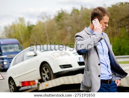 Man calling while tow truck picking up his broken car