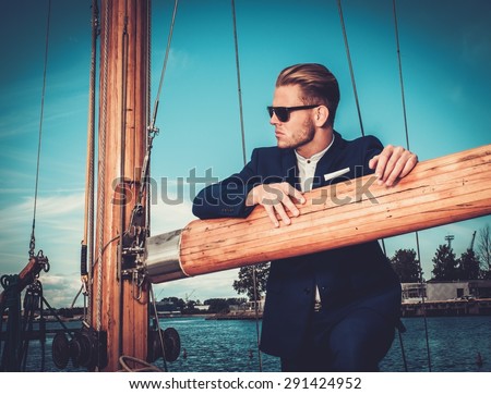 Stylish wealthy man on a luxury wooden regatta