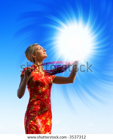 Beautiful blond girl with a magic light sphere over crystal clear blue sky