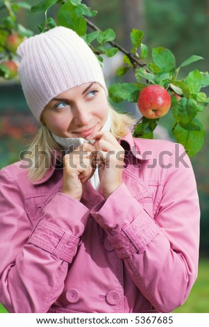 Young girl in pink coat near the apple tree