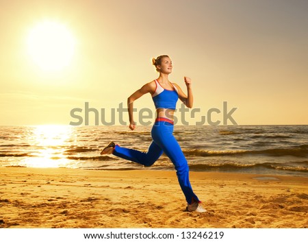 Beautiful young woman running on a beach at sunset (real shot, background is not photoshopped in)