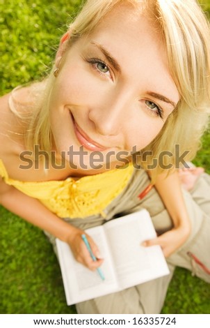 Funny wide angle portrait of a young woman reading book outdoors