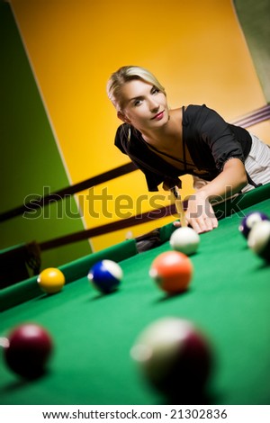 Beautiful blond woman playing billiards