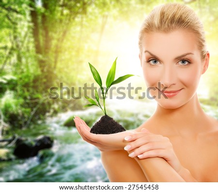 Beautiful woman with young plant in forest