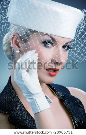 Beautiful young woman in white hat with net veil. Retro portrait