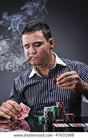 Portrait of a young gangster smoking and playing poker