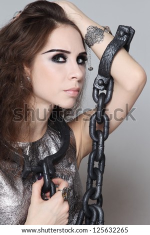 Portrait of young beautiful woman with heavy chain on her neck and arms