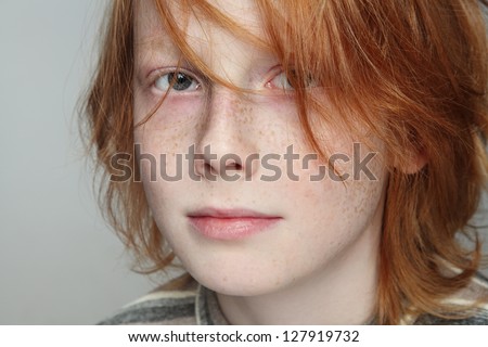 Close-up portrait of sad and thoughtful freckled teen boy