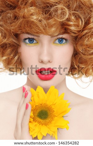 Portrait of young beautiful girl with curly hair and sunflower in her hands