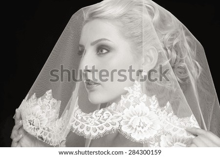 Duotone portrait of young beautiful blonde bride with bridal veil over her face