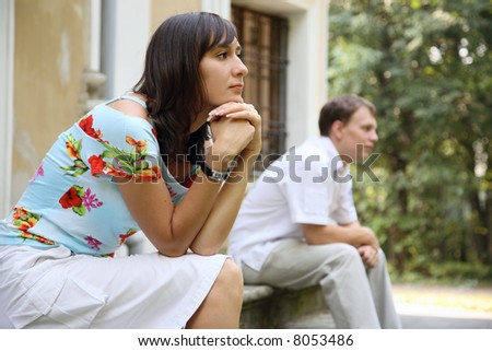 Young sad woman and man sitting on marble steps in park, selective focus