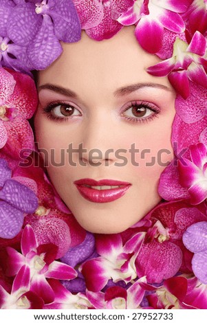 Portrait of beautiful girl with stylish makeup and flowers around her face