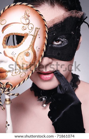 Young woman in mask holding the other venetian mask in hand