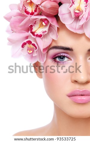 Close-up shot of young beautiful tanned sexy woman with fresh make-up and orchids in her hair, on white background