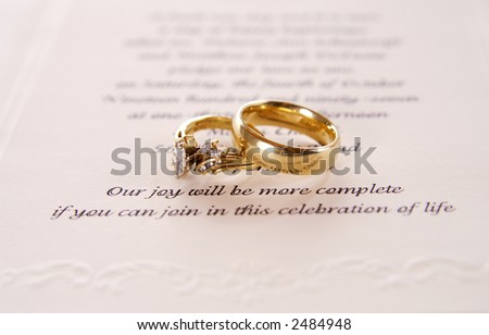 A set of engagement rings on a wedding invitation